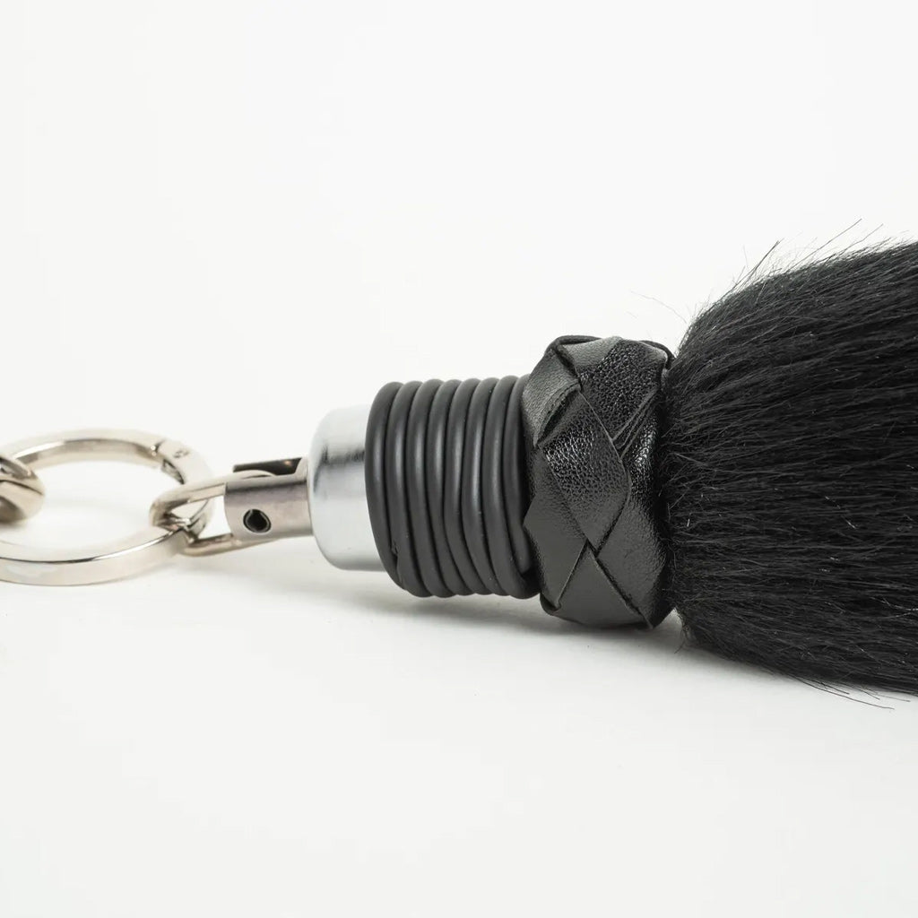 close up of the attachment of a faux fur foxtail finger flogger against a white background.