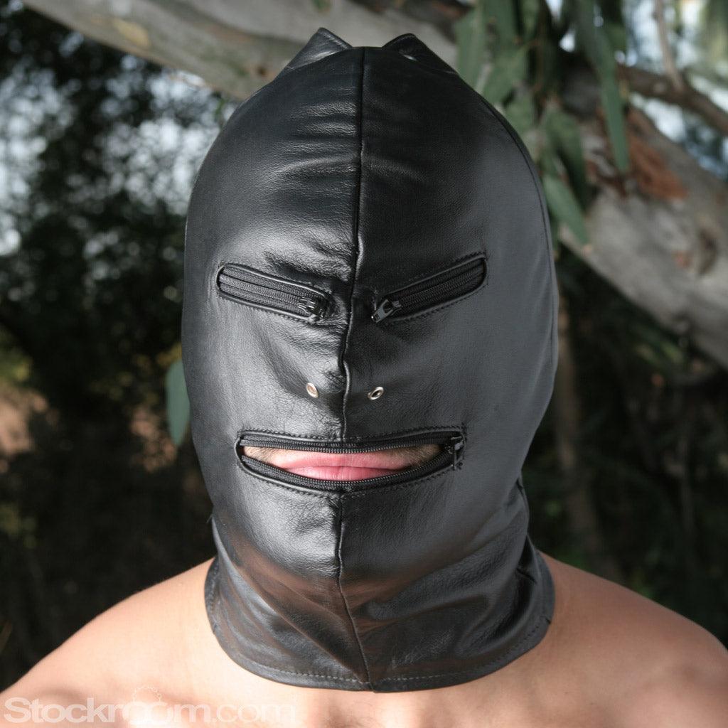 A man wearing the black leather Jack the Zipper Bondage Leather Hood is shown. The hood completely covers his face, head, and neck. The hood has nostril holes and zippers over each eye and one over the mouth, which is open.