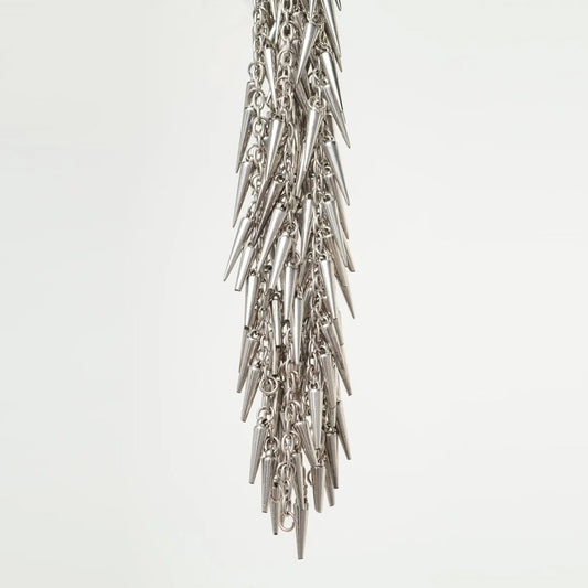 close up detail of silver flogger with spike-like elements on a light gray background