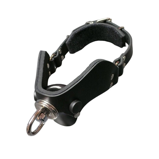 The Half Moon Bit Gag By Scott Paul Designs is displayed on a grey table. The exterior of the gag is lined with black leather, and the interior has black padding on the front of the gag and behind the buckle.