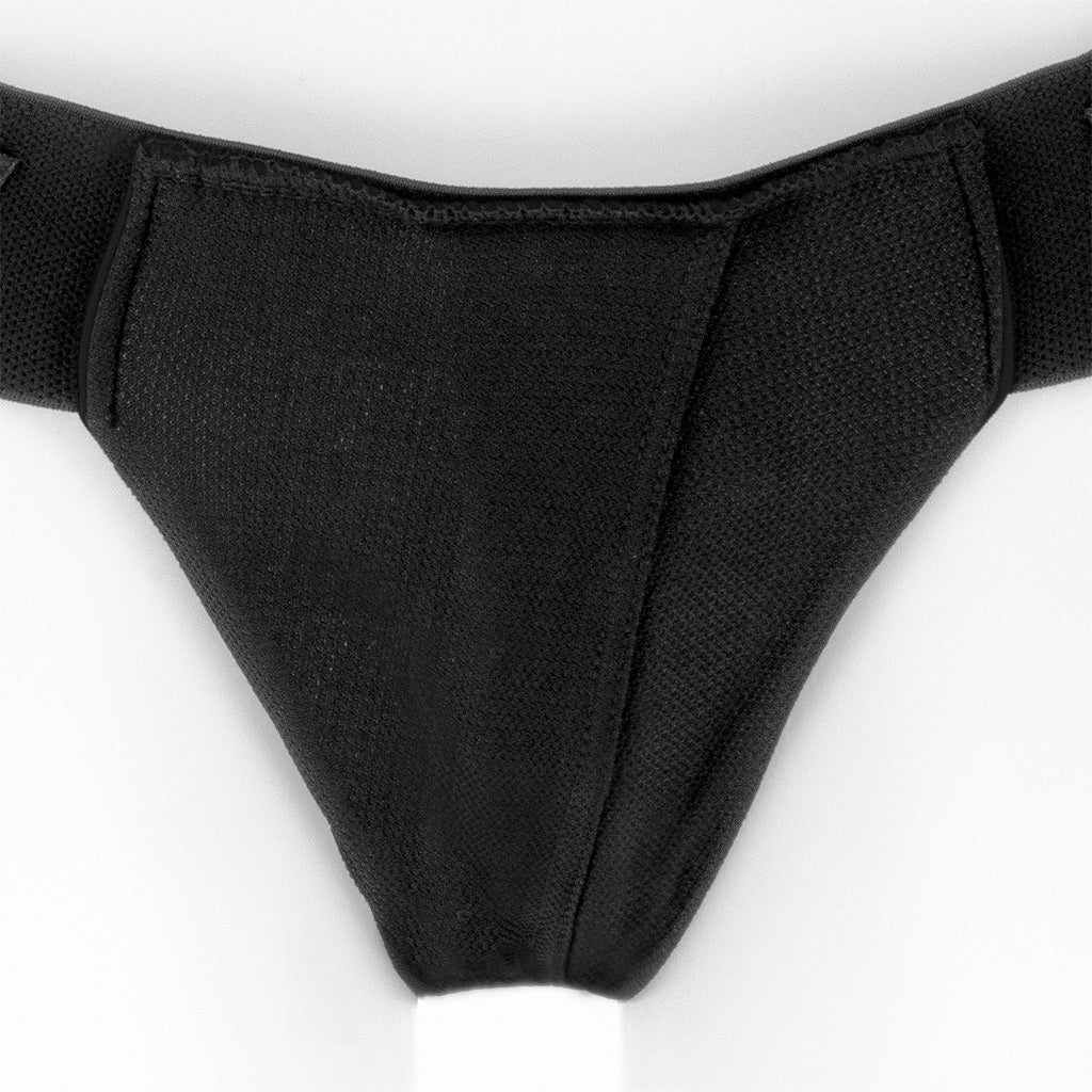 Close-up of  black cloth SpareParts dildo harness from the back, against a white background.