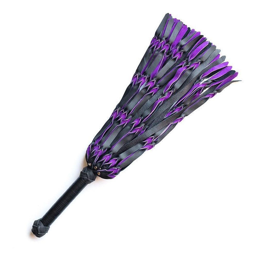 The purple and black Braided Leather Flogger is displayed against a blank background. The flogger’s falls are made of strips of black and purple leather braided together. The handle is long and cylindrical with knots of braided leather and both ends.