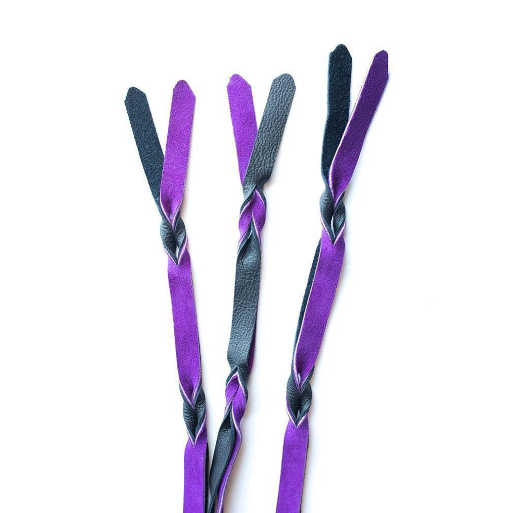 A close-up of the falls on the purple and black Braided Leather Flogger is displayed against a blank background.