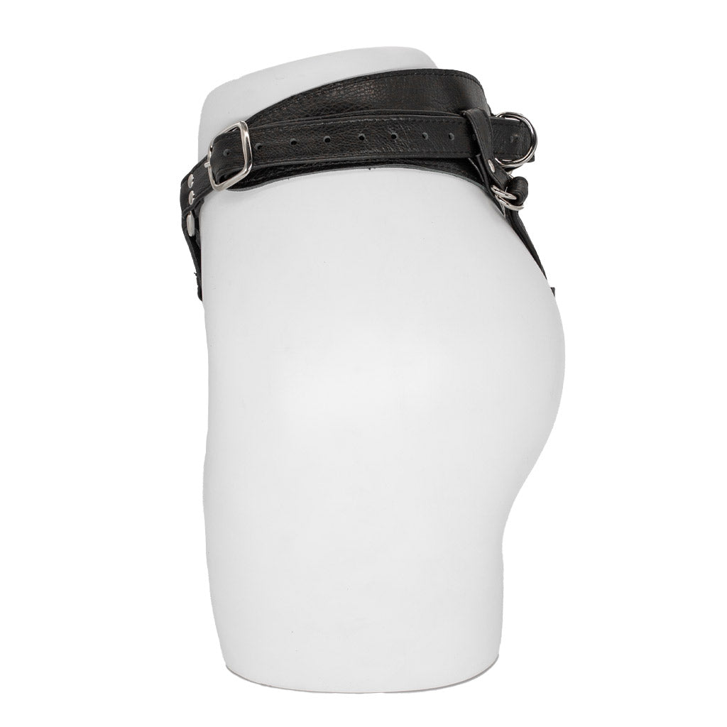 The Minx Licorice Leather Strapon Harness is displayed from the side on the lower half of a mannequin against a blank background. It has an adjustable buckle on the side.