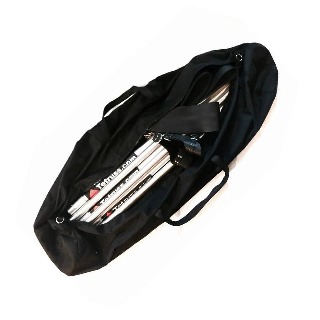 The Tetruss Travel Bag is shown against a blank background. It is a black, cylindrical canvas bag with black straps. It is unzipped and is shown with a Tetruss bondage frame, leather stirrups, and suspension cuffs inside of it.