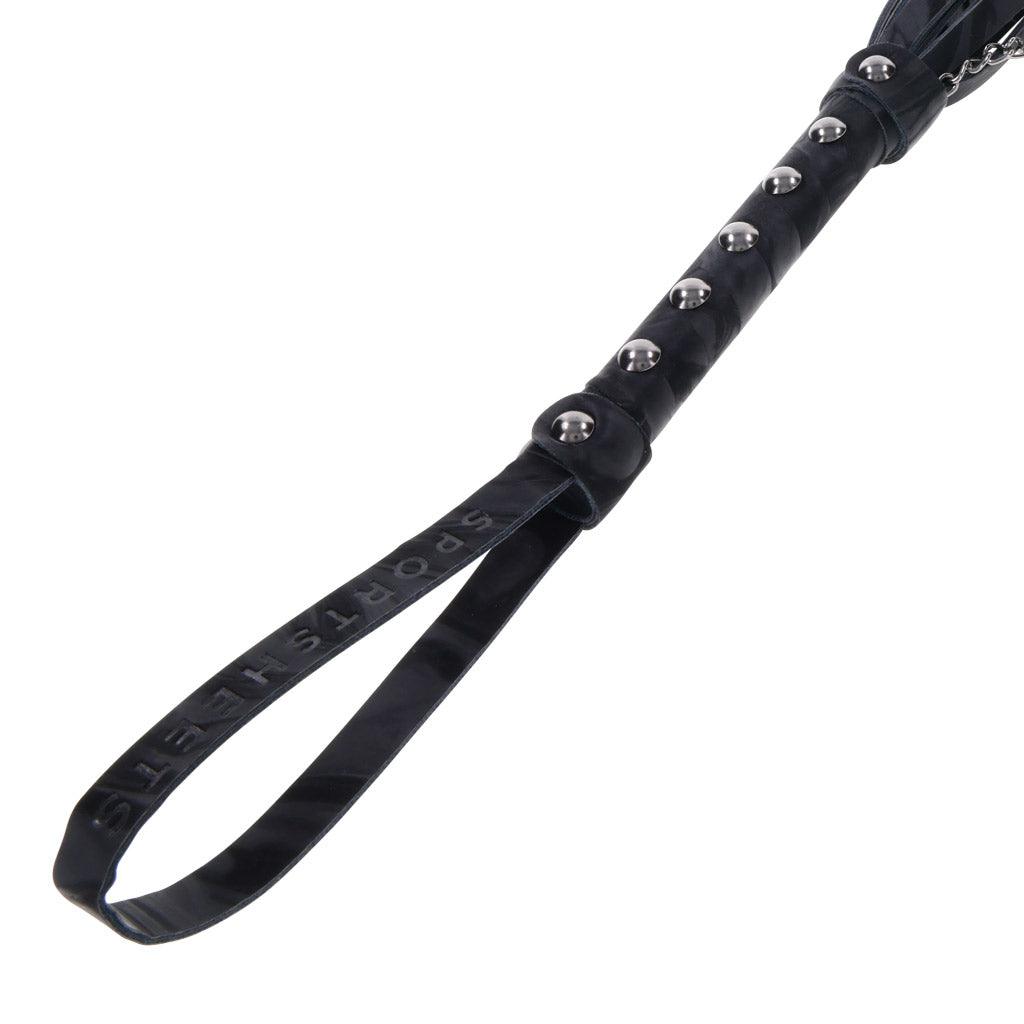 Closeup of the handle of the Velvet Noir Chain Flogger, focused on the wrist strap and the metal studs along the handle.