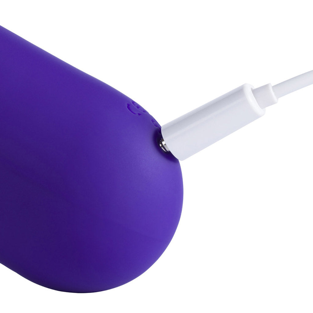 The base of the mini click licking vibrator with a white charging cord plugged in.