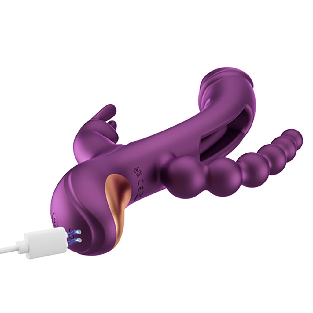 The Trilux Rabbit Vibe on a white background, angled to show the charging contacts at the base. A white charging cord extends from the left side, almost touching them.