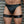 Load image into Gallery viewer, A close-up of a man&#39;s body from his waist to his knees is shown in front of a metal wall. He wears black leather underwear and Leather Thigh Cuffs, which are made of black leather and silver hardware. The cuffs have one small D-ring on the front.
