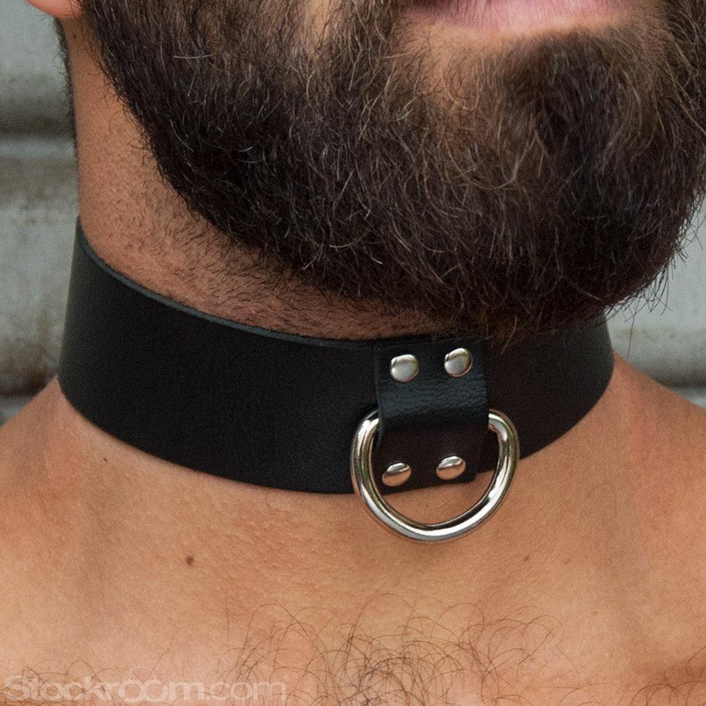 A close-up of a man with dark facial hair's neck is shown. He is wearing the black Locking Leather Collar.