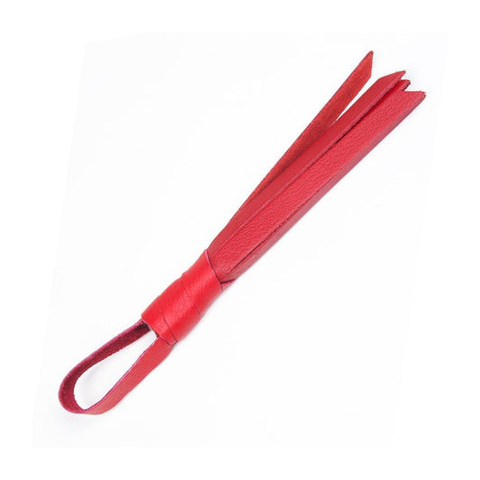The red Teeny Weeny Leather Flogger from The Stockroom is shown against a blank background. It is a mini flogger made of red leather with a tiny handle and loop at the end.