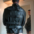 Load image into Gallery viewer, A man wearing the Premium Leather Straitjacket faces a mirror with his reflection visible. The jacket has four adjustable buckling straps across the back and one around the neck.