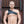 Load image into Gallery viewer, A man with buzzed hair and a blonde beard stands in front of a metal wall wearing The Gladiator Chest Harness. The harness is made of black leather with silver buckles. It sits above his pecs and slings over one shoulder.
