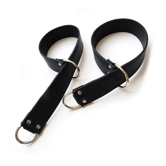 A pair of Garment Leather General Purpose Bondage Straps are shown against a blank background. They are wide strips of black leather with a metal D-ring on each end. One end of the strap has been pulled through the opposite D-ring to create a loop.