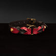 Load image into Gallery viewer, The Melanie Rose Designs x The Stockroom Collar, made of red and black leather braided together with a gold O-ring in the center, is displayed against a black background.
