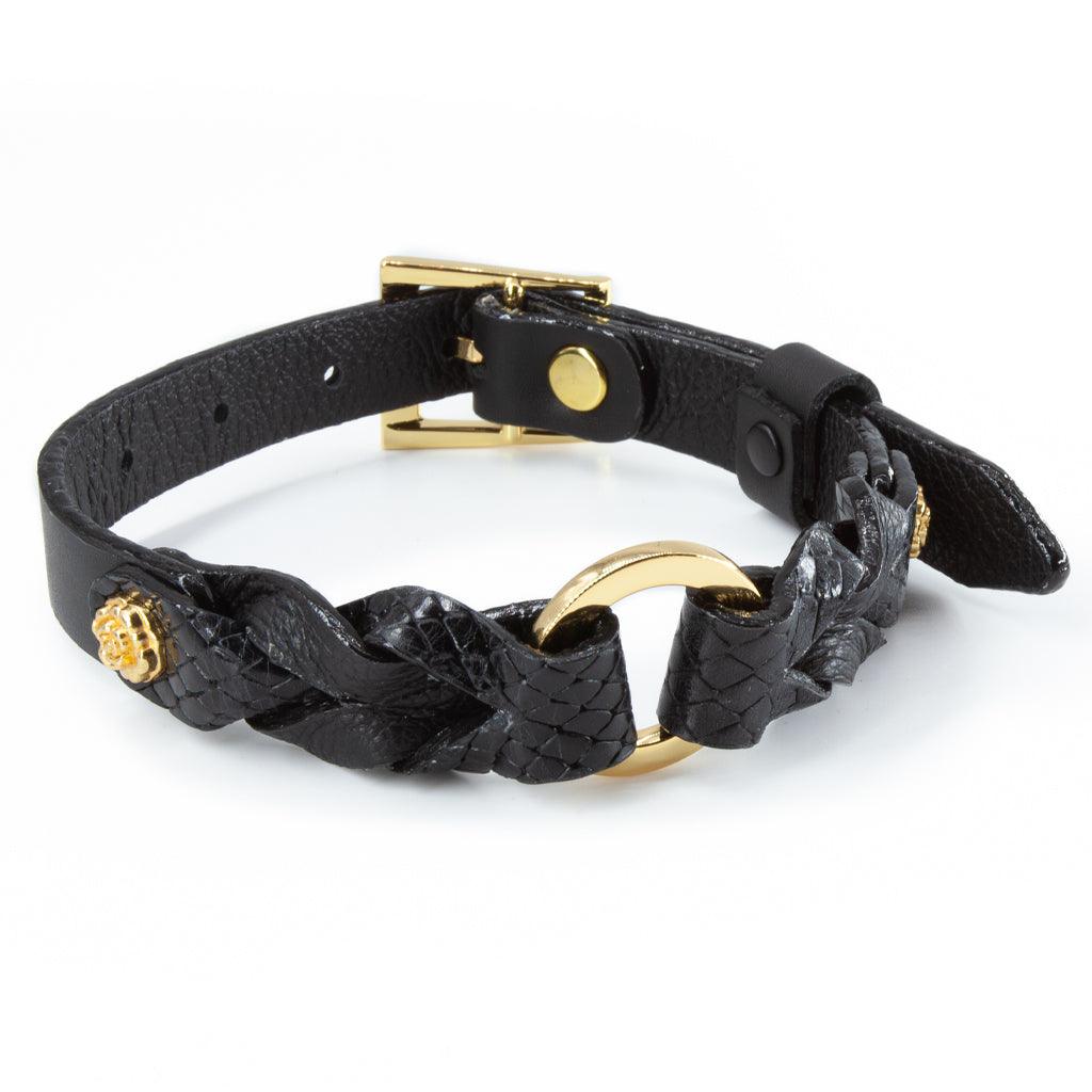 A collar made of black braided leather, with gold-colored hardware, resting on a white surface.