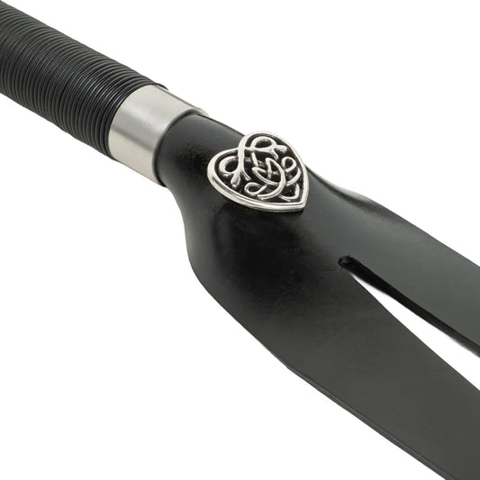 Black fork shaped whip close up photo with decorative heart-shaped handle on a white background