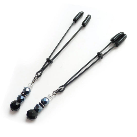 A pair of black Beaded Nipple Clamps are displayed against a blank background. They are adjustable tweezer-style clamps with rubber tips with a decorative string of beads dangling from the bottom of each clamp.