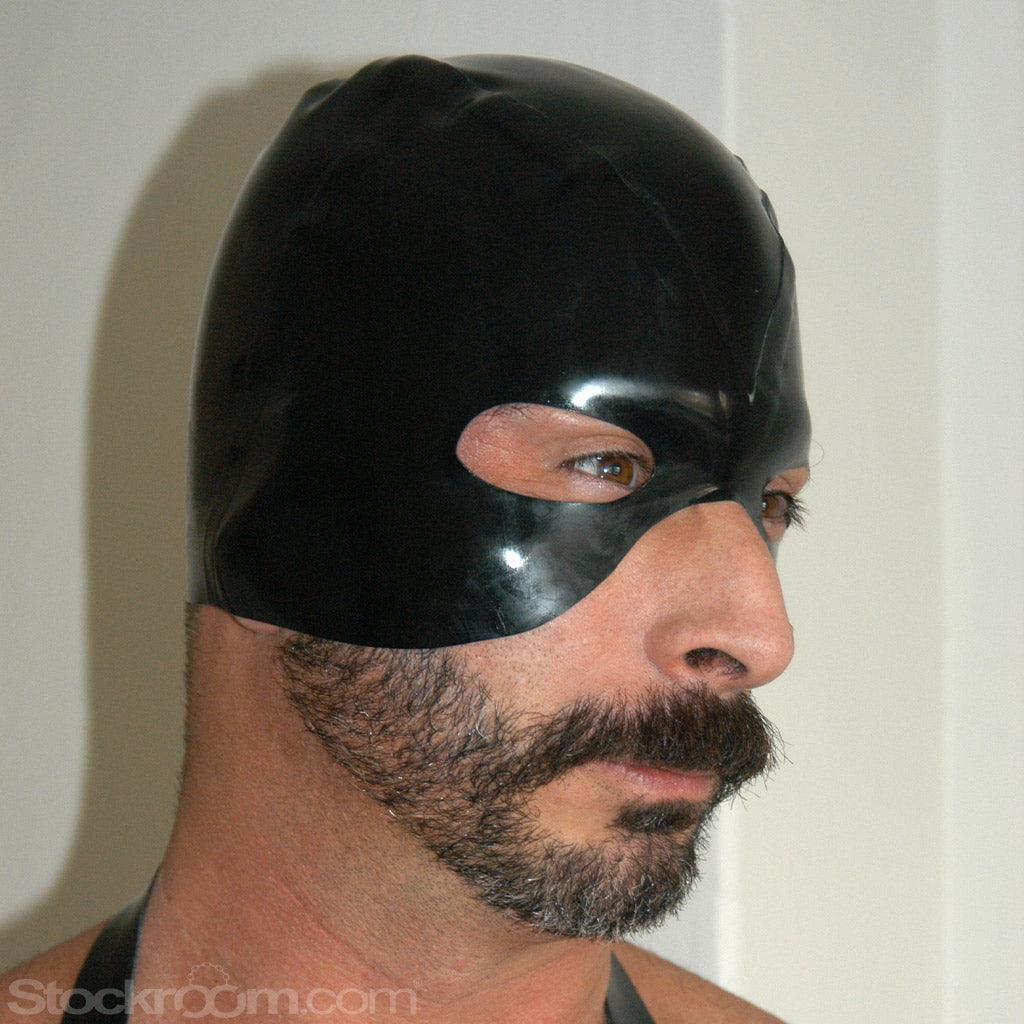 A close-up of a man with facial hair wearing the black Rubber Executioner's Hood is shown. The hood covers the top half of his head, surrounding his eyes and cutting off at the top of his nose.