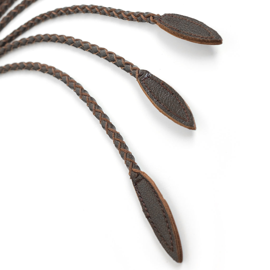 A close-up of the ends of the falls of the Brown Leather Braided Whip are displayed against a blank background.