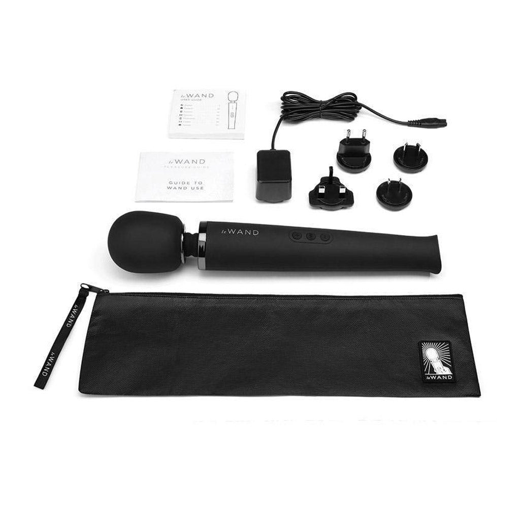 A Le Wand Rechargeable Vibrating Massager in Black is shown against a blank background with the included zipper storage pouch, manual, and power adaptors..