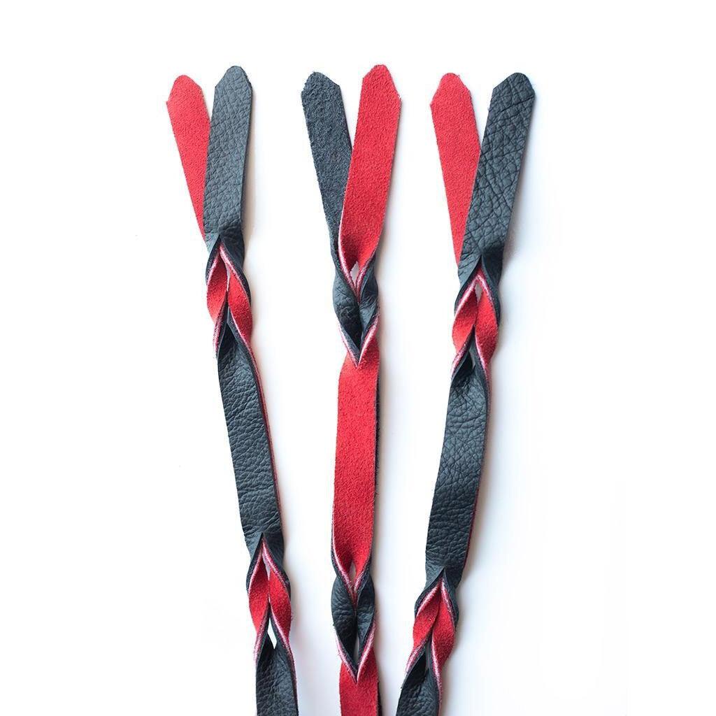 A close-up of the falls on the red and black Braided Leather Flogger is displayed against a blank background.