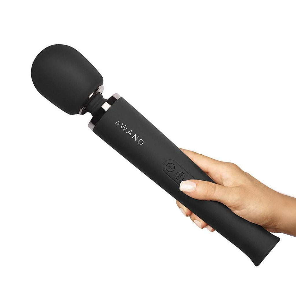 A hand is holding a Le Wand Rechargeable Vibrating Massager in Black against a blank background.
