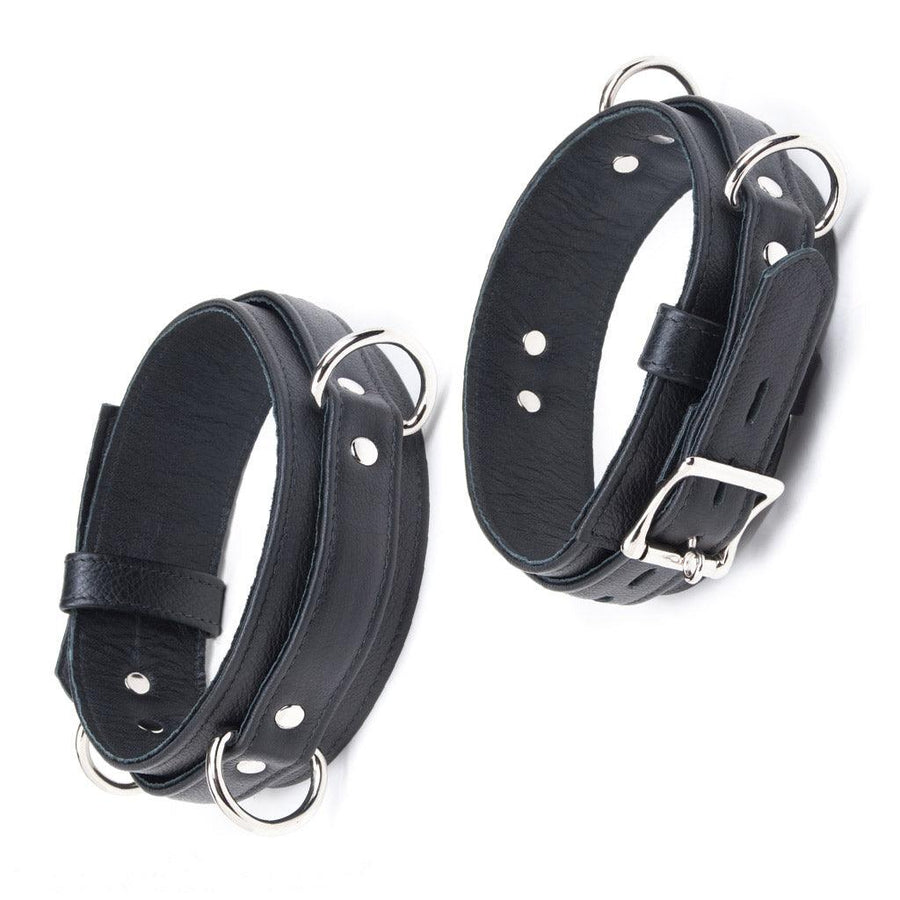 The Premium Garment Leather Locking Thigh Restraint set in black is displayed against a blank background. It is a thick band of black leather with silver metal hardware. The cuff has three evenly spaced D-rings.