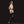 Load image into Gallery viewer, A topless woman with brown hair stands facing away from the camera with her hands on her hips. She is wearing black latex stockings and gloves, the Nancy Strapon Harness with a black dildo attached, and high heels. Her head is turned to look at the camera.
