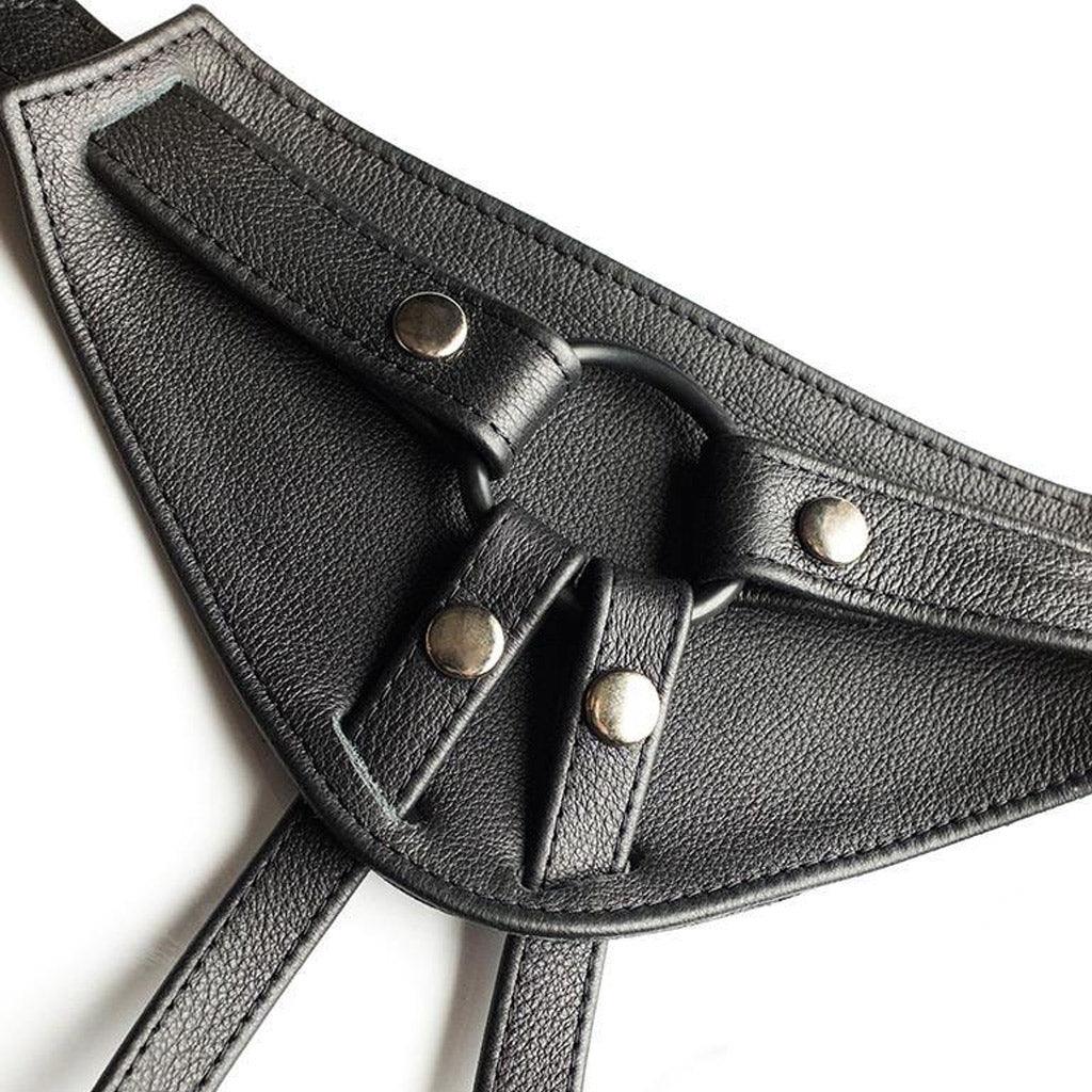 A close-up of the front piece of The Full Curves Leather Strap-on Harness in black is displayed against a blank background.