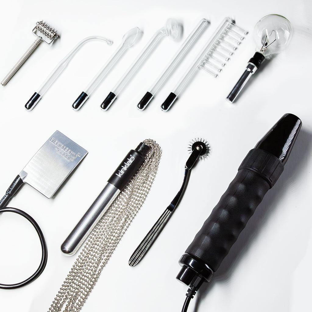 The black-handled Neon Wand is laid on a white surface with the ten electrodes included with the Agent Noir™ kit.