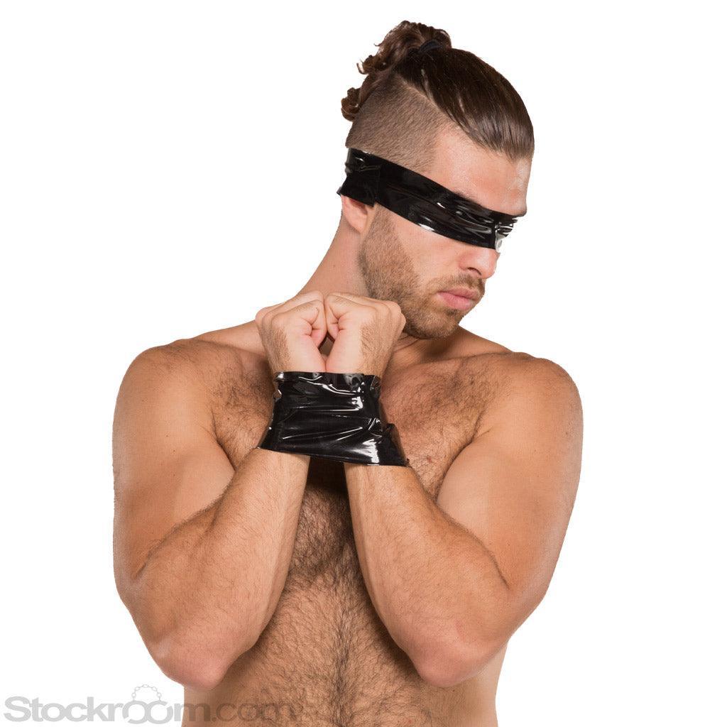 A nude man with dark hair is shown against a blank background. His arms are pulled together in front of him, and his wrists are wrapped together with black Kinklab Bondage Tape. He also has a piece of tape wrapped around his head, covering his eyes.