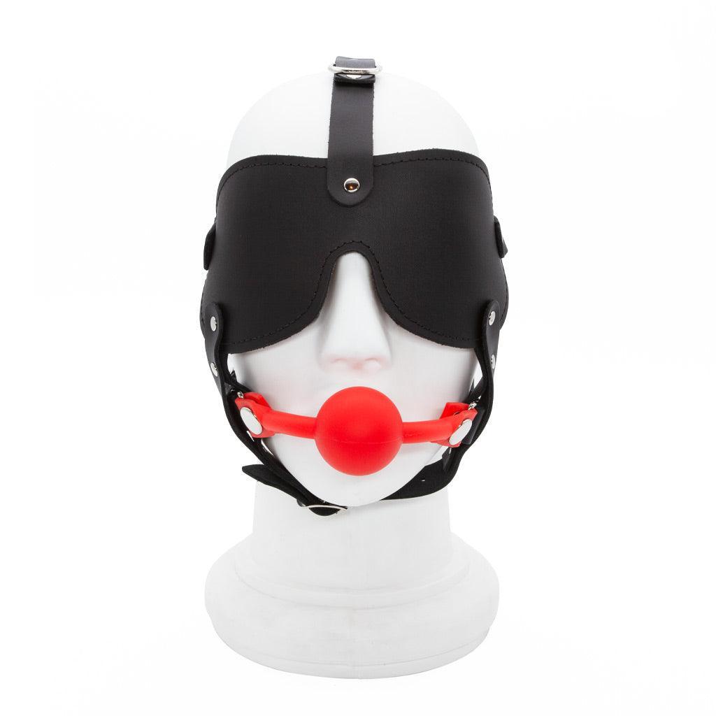 The Silicone Ball Gag And Blindfold Head Harness is displayed on a mannequin head against a blank background. The harness is made of black leather, with a blindfold and straps over the head and under the chin.