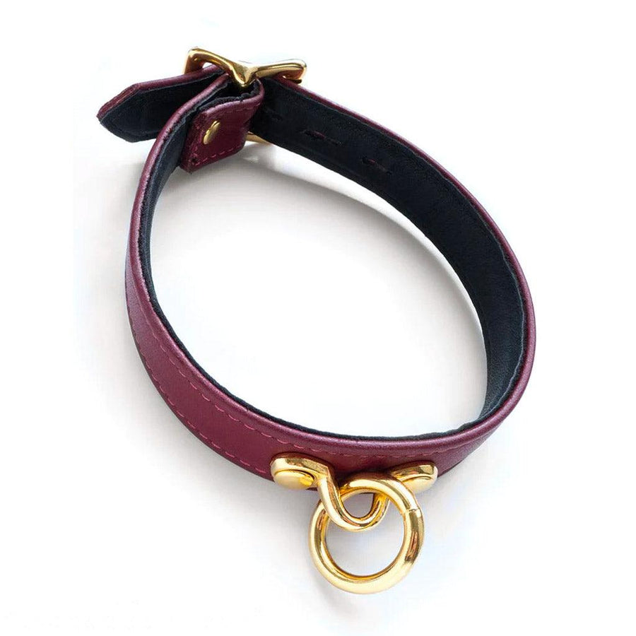 The JT Signature Collection Collar is displayed against a blank background. It is made of Bordeaux leather with gold hardware. The inside of the collar is lined in black leather. There is a small dangling O-ring in the center of the collar.