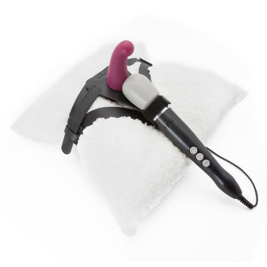 The Wand Thigh Harness made by The Stockroom is shown displayed with the Doxy Vibrating Wand Massager in Black and the KinkLab Ebb & Flow Silicone Dildo in Plum on a white shag pillow.