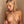 Load image into Gallery viewer, A nude blonde woman stands against a beige tile wall. She is applying the Adjustable Alligator Nipple Clips to her nipple, with her other nipple already in the clamps.
