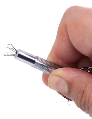 Someone holds an Extreme Talon Nipple Clamp against a blank background, showing a close-up of the exposed claws. The claws, made of five small, metal claws that branch outwards and are bent inwards at a 90-degree angle, emerge from the tip of the clamp.