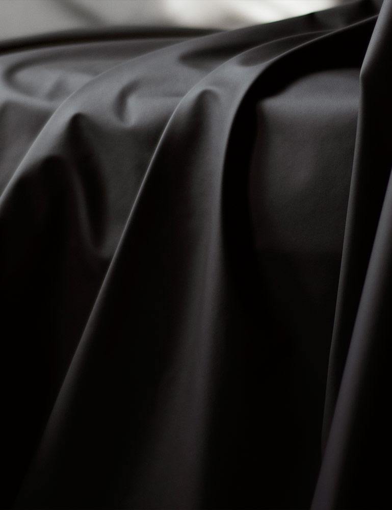 A close-up of the Fluid Proof Protective Throw By Sheets Of San Francisco is shown, displaying the drape and folds of the fabric.