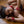 Load image into Gallery viewer, A brunette woman wearing a black bra is shown upside down, lying on her back on a wooden floor. She wears the Red Deluxe Buckling Collar and matching wrist cuffs.
