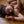 Load image into Gallery viewer, A brunette woman in a black bra is shown lying on a wooden floor. She wears the red leather Locking/Buckling Wrist Cuffs and a matching collar.
