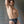 Load image into Gallery viewer, A muscular brunette man is shown standing in front of a metal wall. He has one hand behind his back and the other behind his head. He wears the black Male Leather Thong.
