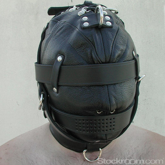 A person's head in the Heavy Duty Leather Hood is shown. It is made of black leather with silver hardware and covers the person's head and neck. Straps are wrapped around the eyes, mouth, neck, and chin. There are small holes for the nose and mouth.