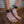 Load image into Gallery viewer, A close-up of a man’s bare feet standing on a wooden floor is shown. There is a metal wall in the background. He has a pawprint tattoo on his lower leg and is wearing the black Premium Garment Leather Ankle Cuffs. They are locked with small silver padlocks.
