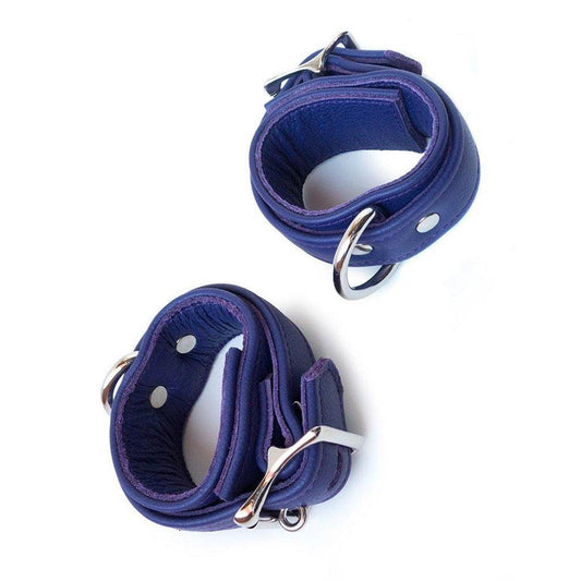 A pair of Premium Garment Leather BDSM Wrist Cuffs are shown against a blank background. They are made of purple leather and silver hardware. Each cuff has an adjustable strap, a lockable buckle closure, and a D-ring.