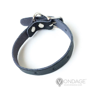 The Vondage Cock Ring is shown from the back against a blank background. It is a thin, adjustable strip of black faux leather with a metal buckle closure.