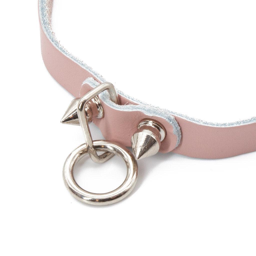 A close-up of the O-ring on the Stupid Cute Choker and the spikes on either side of it is shown against a blank background.
