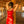 Load image into Gallery viewer, A woman wearing a red latex dress stands in an empty room with brick walls. She leans on one of the wooden poles, holding onto it with her arms above her head. She is wearing the black Open Mouth Leather Bondage Hood, exposing only her mouth and chin.
