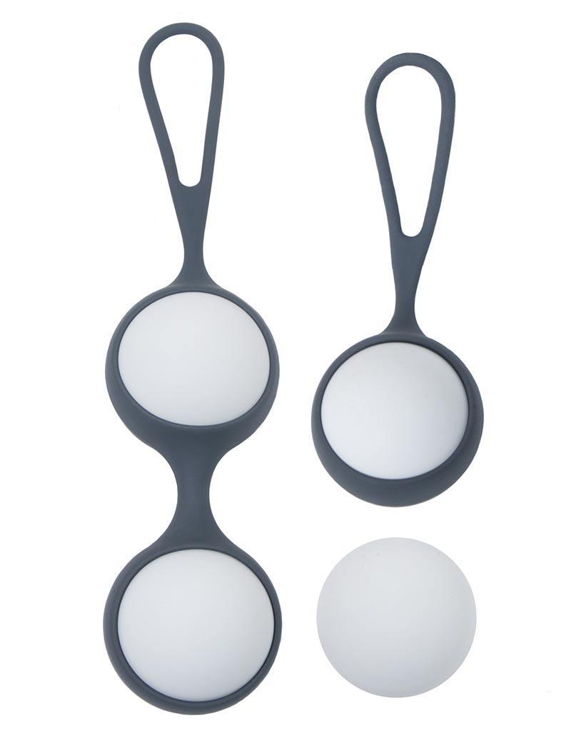 The KinkLab Private Pursuit Kegel Balls are displayed against a blank background. The set comes with two different silicone cases, each with loops on the end. One case holds one ball, and the other holds two.