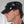 Load image into Gallery viewer, A headshot of a man in front of a white background. He wears the Rubber Soldier&#39;s Cap with Snaps by Syren Latex in black. The hat has a low brim and metal grommet accents on the sides.
