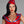 Load image into Gallery viewer, A woman with black hair and red lipstick wearing a red latex top poses in front of a grey background. She also wears the  Latex Garrison Cap by Syren latex in red with blue trim.
